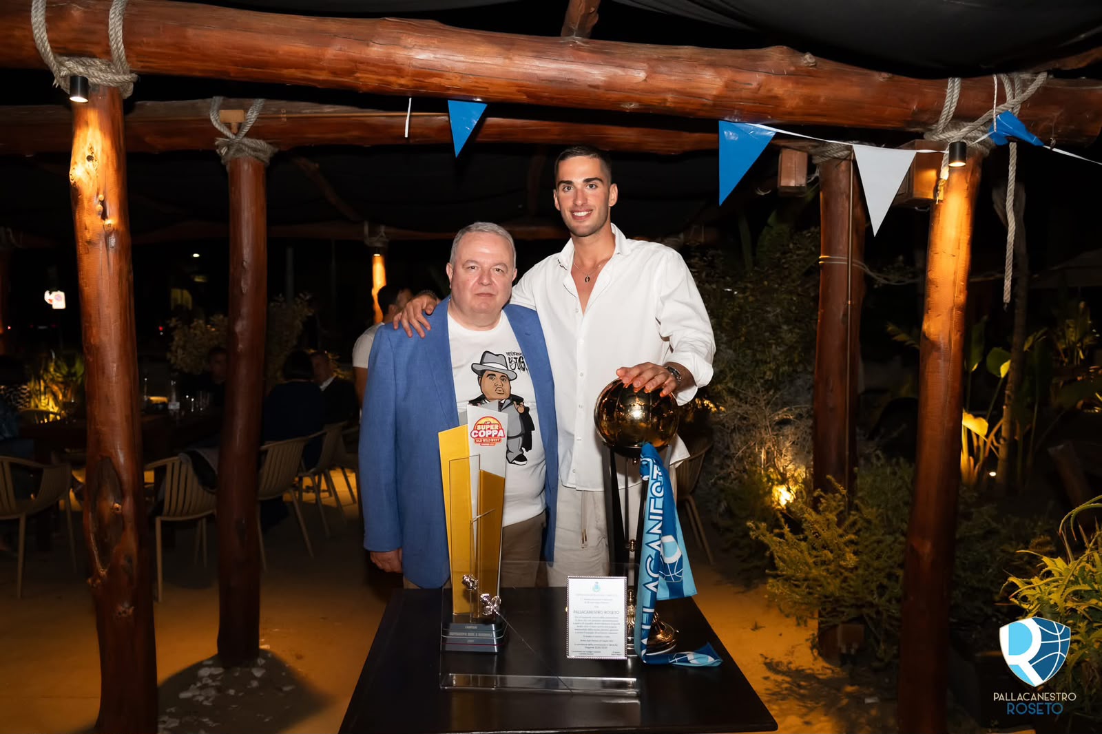 Luigi Lamona posa con un giocatore della Pallacanestro Roseto e la Coppa Italia durante un evento serale